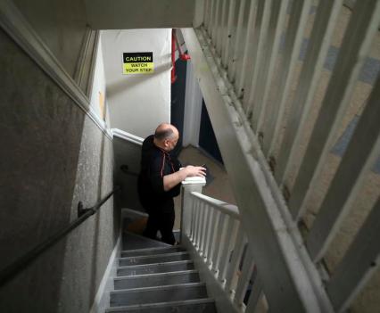 With the elevator out of service, Richard Chapman walks down a narrow staircase at Winton Hotel in San Francisco.
